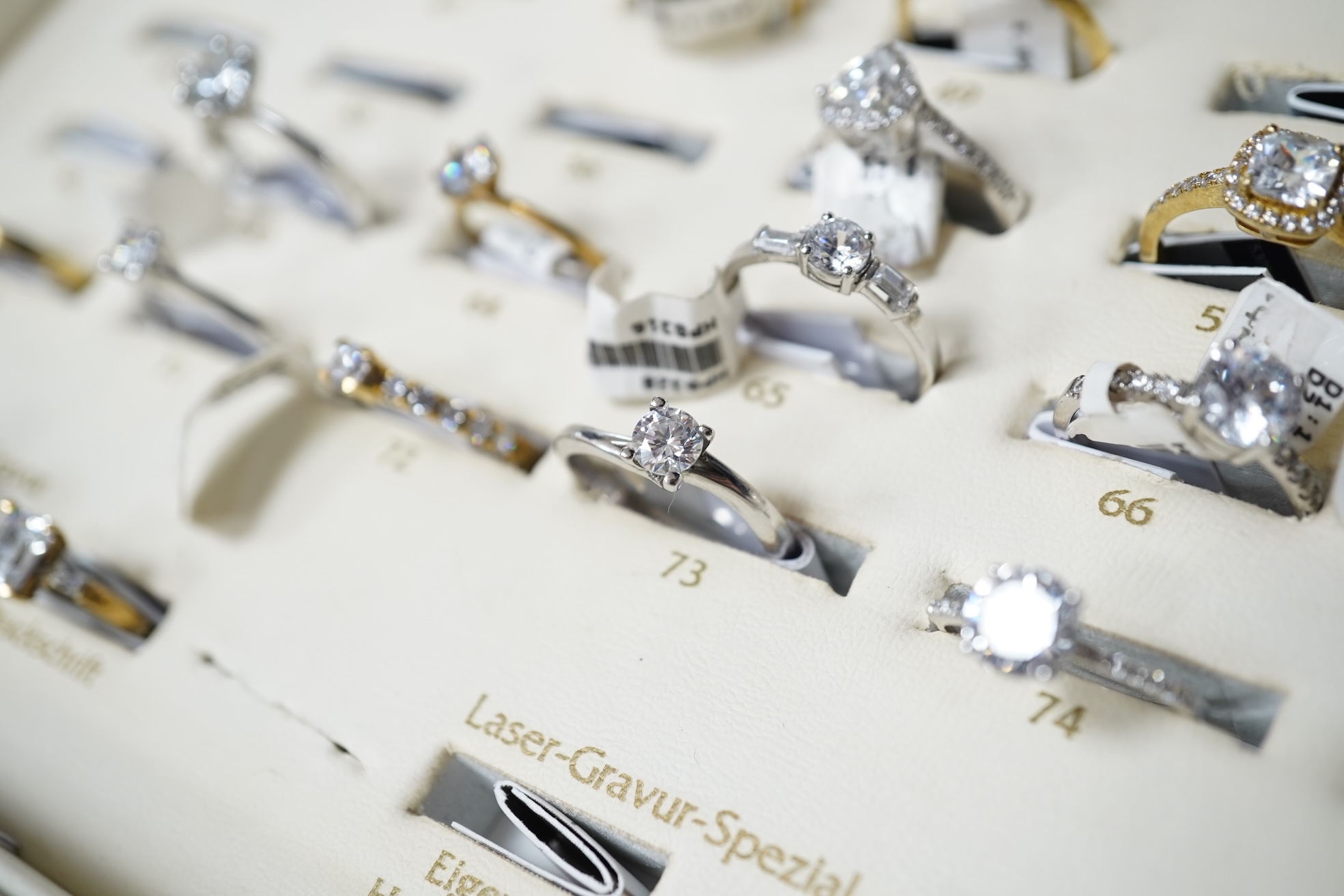 A collection of 22 simulant diamond rings, variously mounted in silver and base metal, one in platinum, British hallmarks, together with a ring display unit